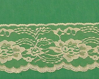 May include: A close-up of a white lace trim with a scalloped edge. The lace features a floral design with delicate details.