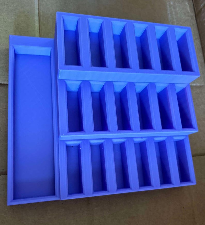 May include: A stackable, lavender-colored organizer with multiple rectangular compartments. The organizer features a tray on the side and is designed to hold small items. The design is simple and functional, suitable for various organizational needs.