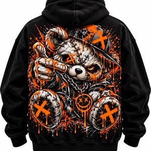 May include: A black hooded sweatshirt featuring a large graphic on the back of a stitched teddy bear wearing a baseball cap. The bear has glowing orange eyes, a silver chain with a smiley face pendant, and is covered in dripping orange paint.