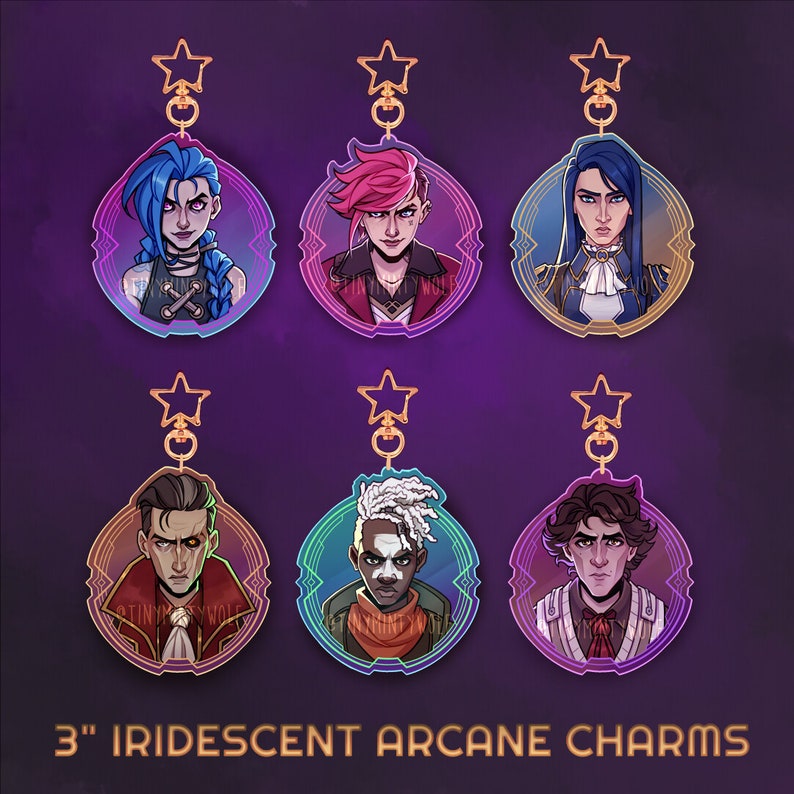 May include: Six iridescent Arcane charms, each 3 inches in diameter, featuring character portraits. The charms have a star-shaped clasp and a decorative border. The characters have blue, pink, and black hair. The text "3" IRIDESCENT ARCANE CHARMS" is at the bottom.