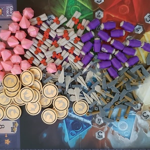 May include: A collection of game pieces for a board game, including purple, pink, and white tokens, gold coins, and grey and brown wooden pieces.