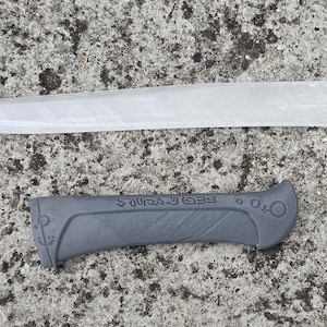 May include: A white plastic knife blade with a black plastic handle. The handle has the text "Fredericks" printed on it.