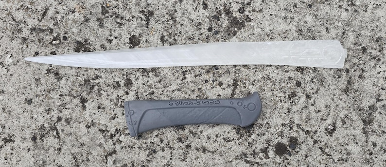 May include: A white plastic knife blade with a black plastic handle. The handle has the text "Fredericks" printed on it.