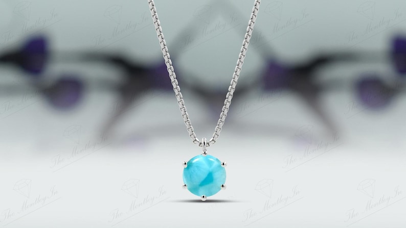 Op de afbeelding: Een zilveren ketting met een ronde blauwe edelsteen hanger. De edelsteen heeft een draaiende vorm en is gezet in een zilveren bezel.