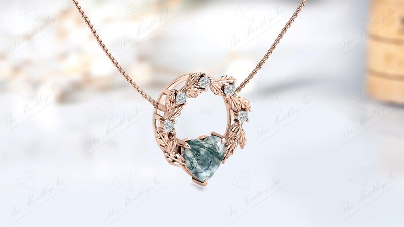 May include: A rose gold necklace with a heart-shaped green agate pendant surrounded by a delicate wreath of leaves and small diamonds.