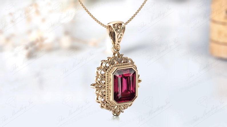 May include: A gold pendant necklace featuring an emerald-cut red gemstone set in a filigree frame.