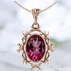 May include: A rose gold pendant necklace with a large oval-shaped pink gemstone set in a delicate, intricate, floral design.