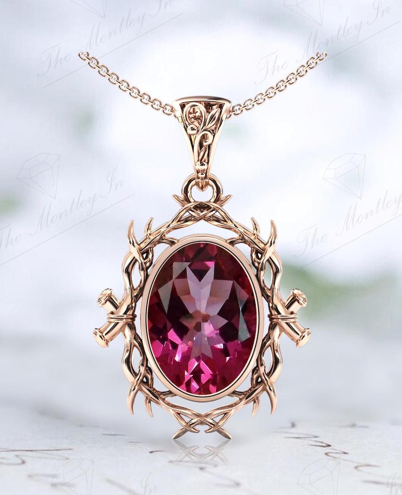 May include: A rose gold pendant necklace with a large oval-shaped pink gemstone set in a delicate, intricate, floral design.