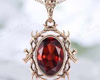 May include: A gold pendant necklace with a large, oval-shaped, red gemstone set in a detailed, ornate, gold frame. The frame is made of twisted, vine-like designs with small, gold accents.