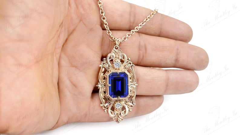 May include: A gold pendant necklace with a large blue gemstone set in a filigree frame. The pendant is ornate and features a detailed design.