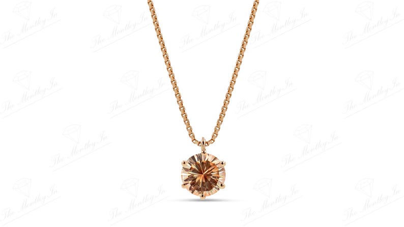 May include: A rose gold necklace featuring a round, light brown gemstone pendant. The pendant is set in a six-prong setting and hangs from a delicate chain. The necklace is displayed against a white background.