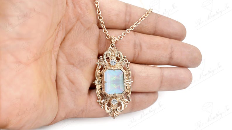 May include: A gold necklace with a large, ornate pendant featuring a white opal gemstone surrounded by smaller clear stones.
