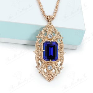 May include: A gold necklace with a large blue gemstone pendant surrounded by smaller clear gemstones. The pendant is in a detailed ornate design.