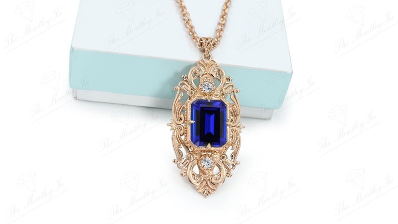 May include: A gold necklace with a large blue gemstone pendant surrounded by smaller clear gemstones. The pendant is in a detailed ornate design.