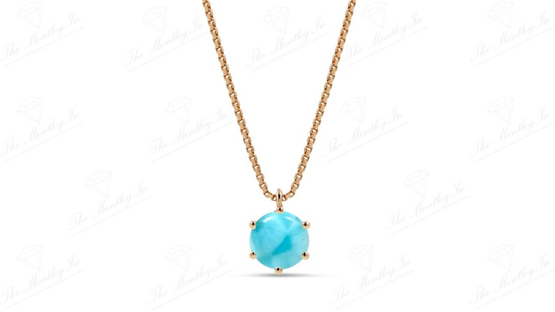 Op de afbeelding: Een gouden ketting met een blauwe edelsteen hanger. De hanger is rond en heeft een facetgeslepen ontwerp.