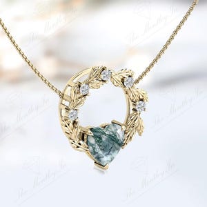 May include: A gold necklace with a heart-shaped green agate pendant surrounded by a wreath of leaves and small diamonds.