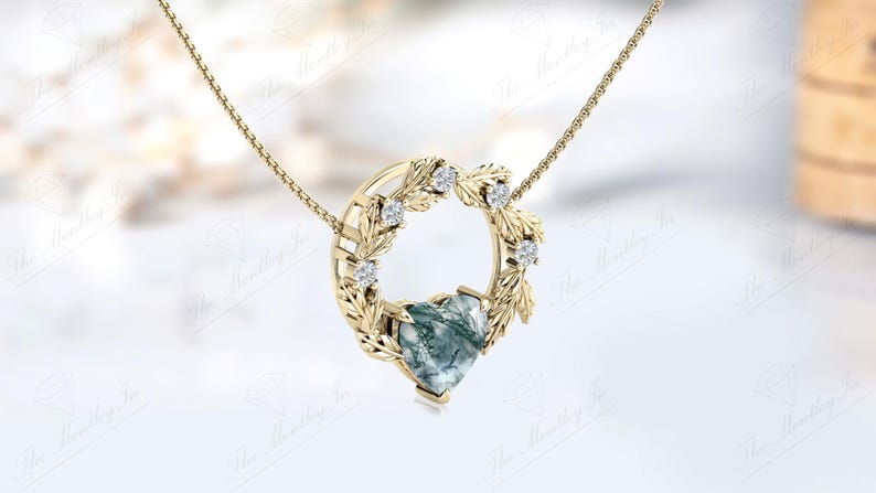 May include: A gold necklace with a heart-shaped green agate pendant surrounded by a wreath of leaves and small diamonds.