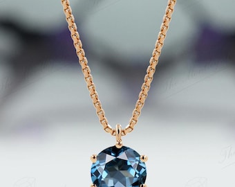 May include: A rose gold chain necklace with a round blue topaz pendant.