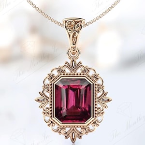 May include: A gold pendant necklace featuring a large, deep pink, emerald-cut gemstone set within an intricate, ornate, gold frame.