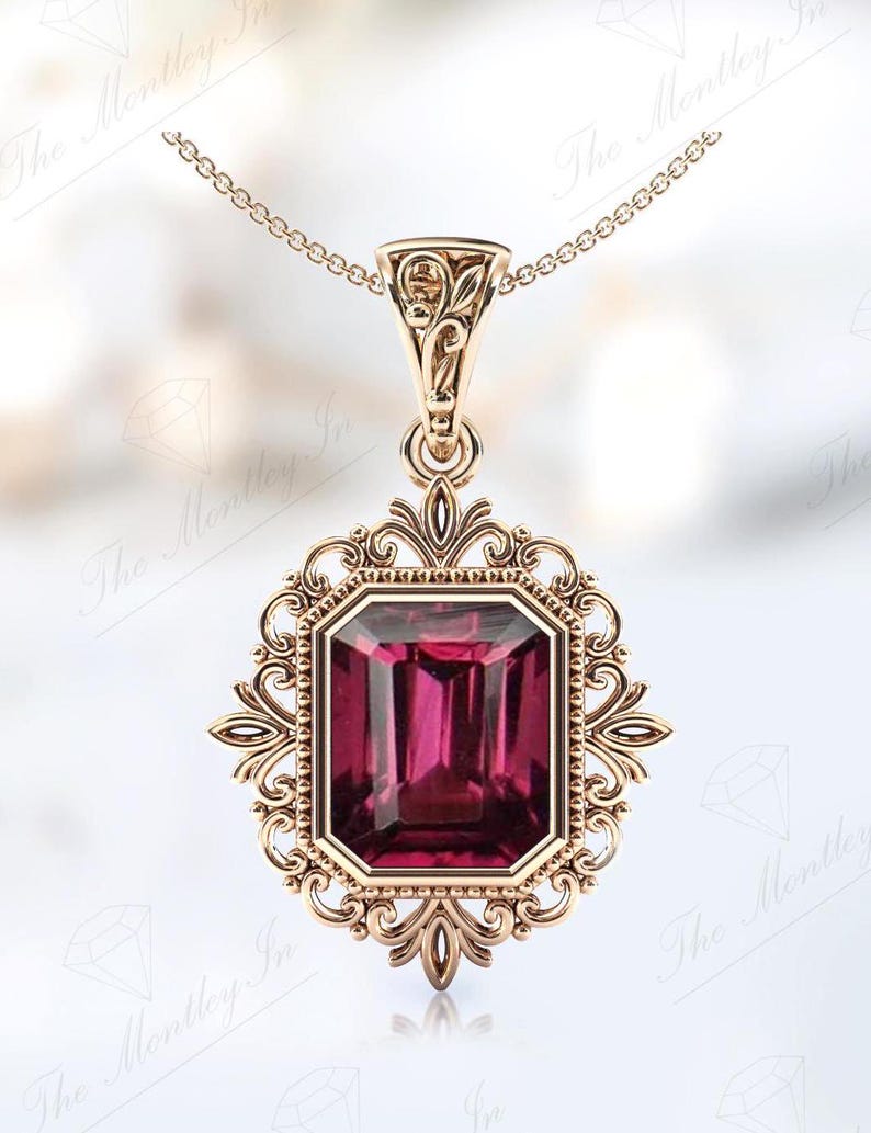 May include: A gold pendant necklace featuring a large, deep pink, emerald-cut gemstone set within an intricate, ornate, gold frame.
