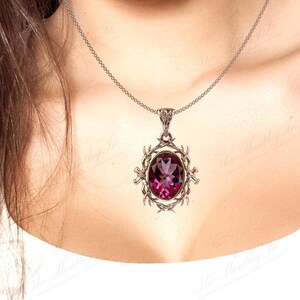 May include: A silver chain necklace with a pendant featuring a large, oval-shaped, purple gemstone set in a silver filigree design.