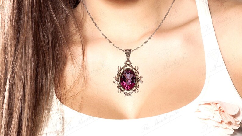 May include: A silver chain necklace with a pendant featuring a large, oval-shaped, purple gemstone set in a silver filigree design.