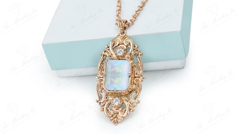 May include: A gold-tone necklace with a large, ornate pendant featuring a rectangular, iridescent white stone surrounded by smaller clear stones.