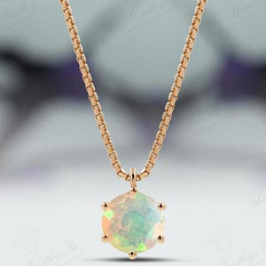 May include: A delicate gold chain necklace with a round opal pendant. The opal is a pale green and white colour with a slight shimmer.