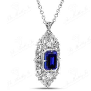 May include: A silver pendant necklace with a blue gemstone set in a filigree design. The pendant is surrounded by smaller white gemstones.