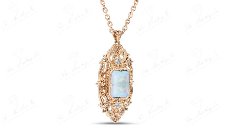 May include: A gold pendant necklace with a large, rectangular, iridescent opal gemstone set in a detailed, ornate, filigree frame. The frame is accented with two smaller, round, clear gemstones.