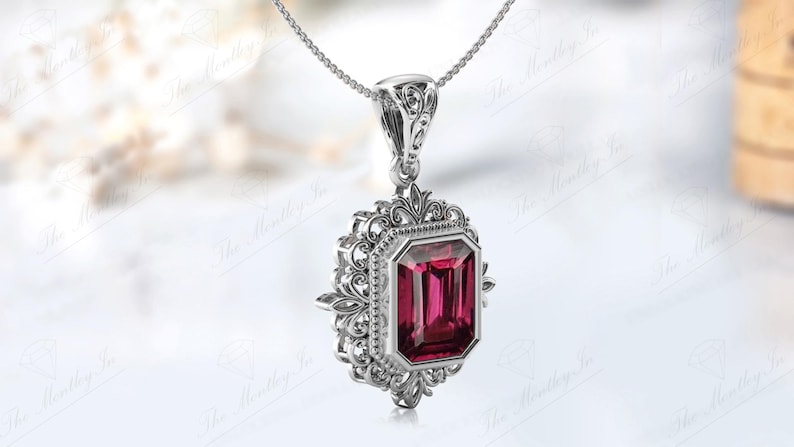 May include: A silver pendant necklace featuring an intricate filigree design and a large, rectangular, emerald-cut, pink gemstone.