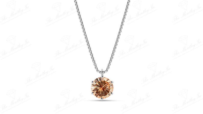 May include: A silver necklace with a round, light brown gemstone pendant. The pendant is set in a silver bezel and hangs from a delicate silver chain. The gemstone has multiple facets.