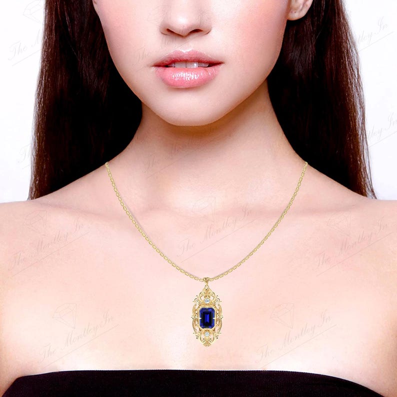 May include: A gold necklace with a pendant featuring a large, dark blue gemstone surrounded by smaller, clear gemstones. The pendant is in a detailed, ornate design.