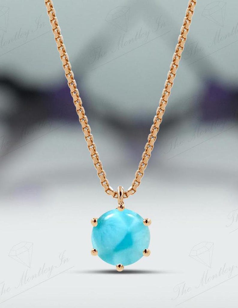 Op de afbeelding: Een delicate gouden ketting met een ronde blauwe edelsteen hanger. De hanger is gezet in een gouden bezel met vier klauwen.