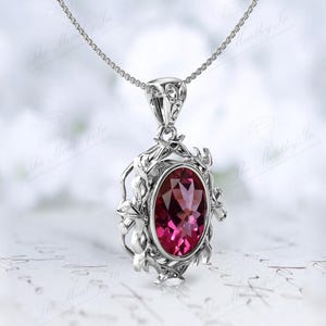 May include: A silver pendant necklace with a pink oval gemstone set in a delicate floral design.