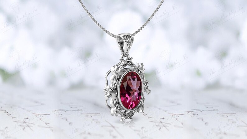 May include: A silver pendant necklace with a pink oval gemstone set in a delicate floral design.