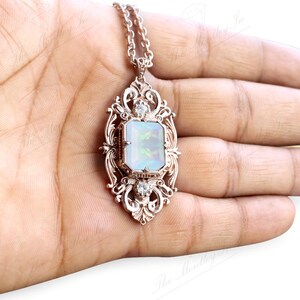 May include: A silver pendant necklace with a large, rectangular, iridescent opal stone set in a detailed, ornate frame. The pendant is on a silver chain.