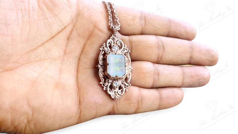 May include: A silver pendant necklace with a large, rectangular, iridescent opal stone set in a detailed, ornate frame. The pendant is on a silver chain.