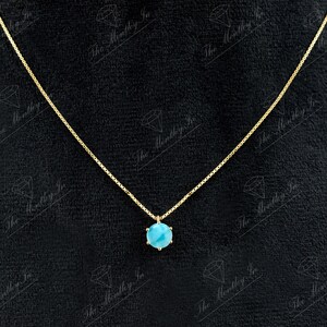 Op de afbeelding: Een gouden ketting met een hanger van turquoise edelsteen. De hanger is een ronde, gefacetteerde steen die in een gouden zetting is gezet.