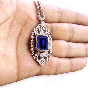 May include: A silver pendant necklace with a large blue gemstone set in a filigree frame. The pendant is on a silver chain.
