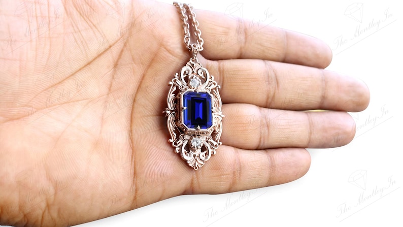 May include: A silver pendant necklace with a large blue gemstone set in a filigree frame. The pendant is on a silver chain.