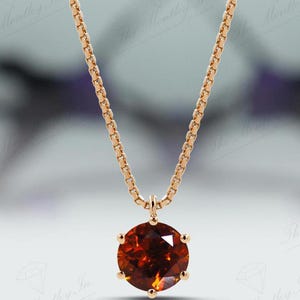 May include: A gold chain necklace with a round, orange gemstone pendant.