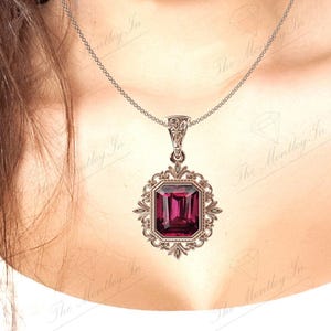 May include: A silver chain necklace with a pendant featuring a large, dark purple, emerald-cut gemstone set in a silver filigree frame.