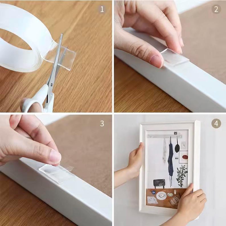 May include: A four-step guide on how to use clear adhesive strips to hang a picture frame. The steps are numbered 1 through 4. Step 1 shows a roll of clear adhesive tape being cut with scissors. Step 2 shows a hand applying a clear adhesive strip to the back of a white picture frame. Step 3 shows a hand applying a clear adhesive strip to the wall. Step 4 shows a picture frame hanging on a wall.