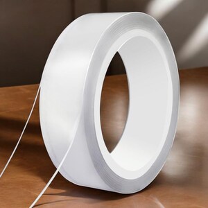 May include: A roll of clear, transparent adhesive tape with a silver backing. The tape is rolled up and the end is visible.