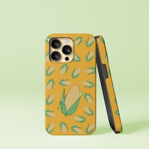 Puede incluir: Una funda de teléfono amarilla con un patrón de mazorcas de maíz. La funda tiene una protuberancia de cámara negra con tres lentes.