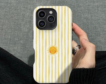 May include: A white and yellow striped phone case featuring a smiling sun graphic. The case has a protective design and is made for a smartphone. The case is held in a person's hand.