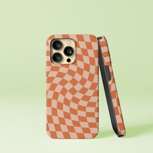May include: A phone case with a swirling checkered pattern in shades of orange and beige. The case has a black bumper and a cutout for the camera lens.