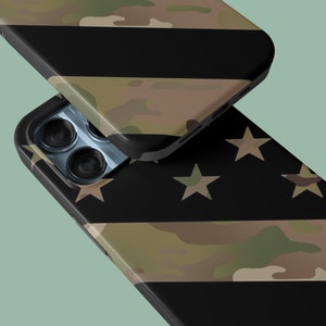 May include: A black phone case with a camouflage pattern and a design of stars on a black background. The phone case has a raised camera bump with three lenses.