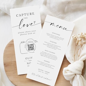 Puede incluir: Dos tarjetas de menú de boda blancas y un letrero "Capture the Love" con un código QR para compartir fotos. El menú enumera aperitivos, entrantes, platos principales y postres. Las tarjetas están sobre una superficie de madera con una servilleta blanca y flores secas.